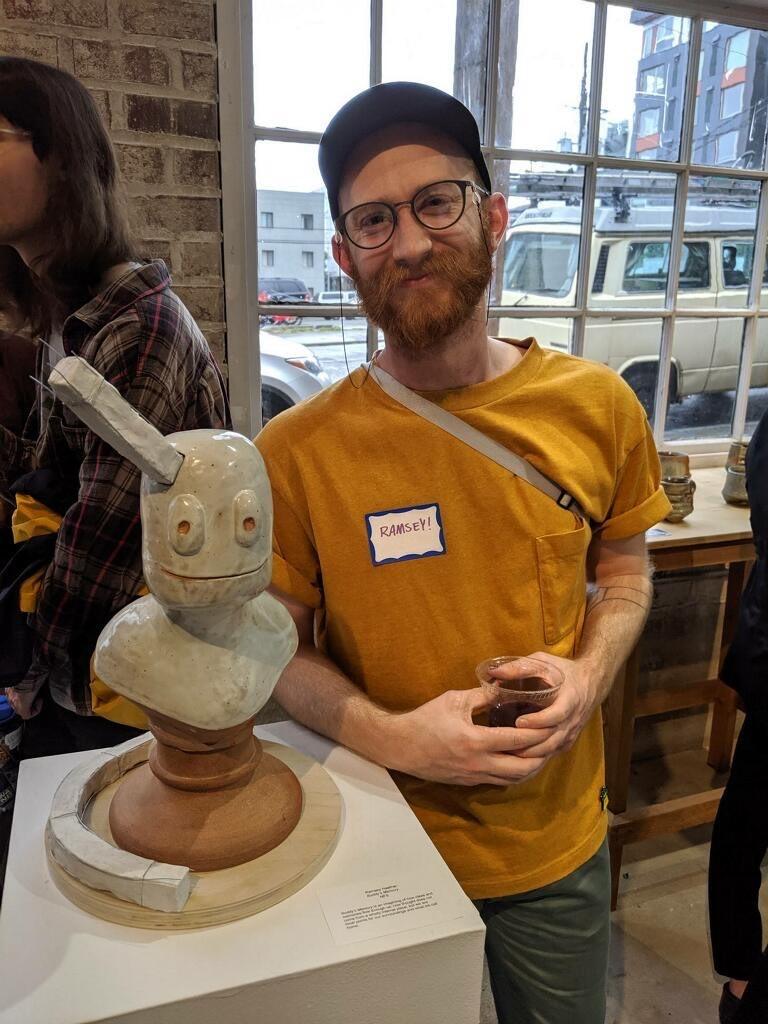 Frye Art Museum supporter, Ramsey Haefner, standing with a ceramic piece at an art show 