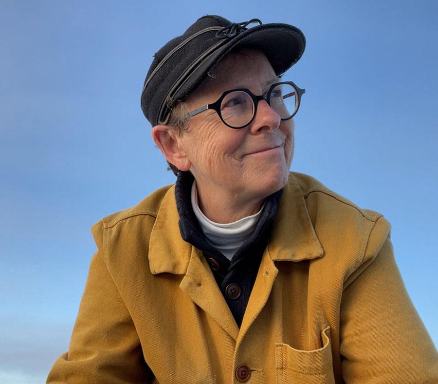 A person wearing a hat, eyeglasses, and a yellow jacket