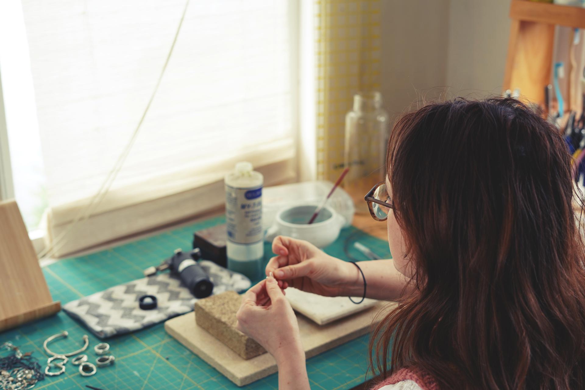 Photo looking over Devon Simpson's shoulder while she works at a jewelry bench