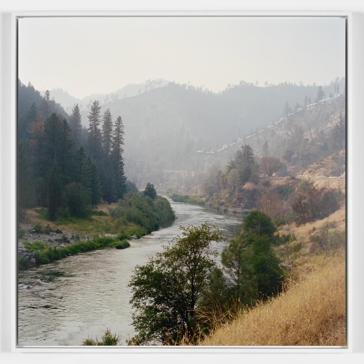 Photograph of a winding river with trees and grasses and hills surrounding it