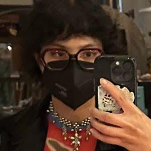 A blurry photograph of a person wearing a respirator holding their phone up to take a photo