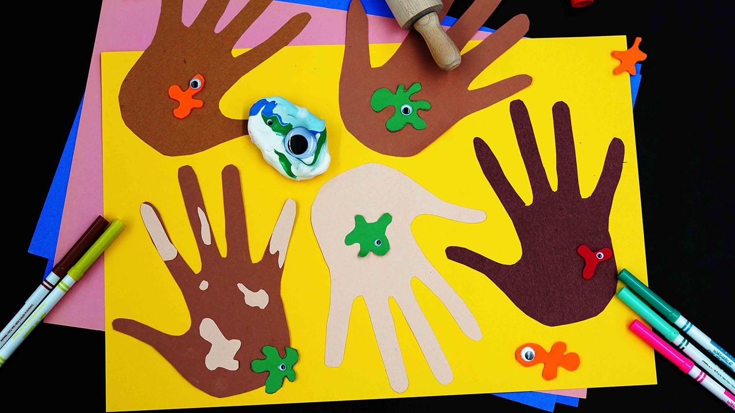 Hand shapes cut out of construction paper on more pieces of construction paper, along with crafting tools