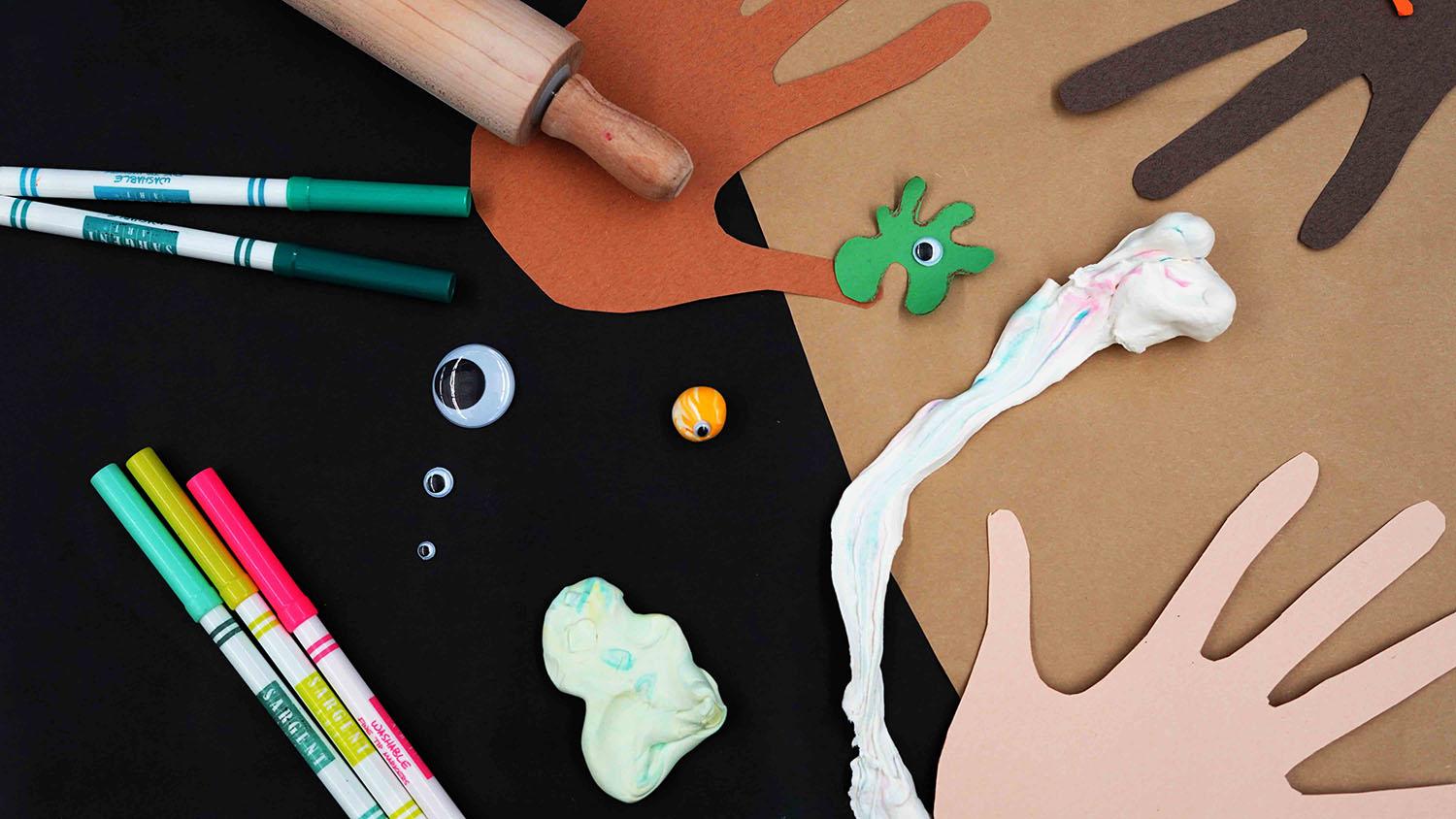 Construction paper hands and more craft materials including pens, clay, and googly eyes