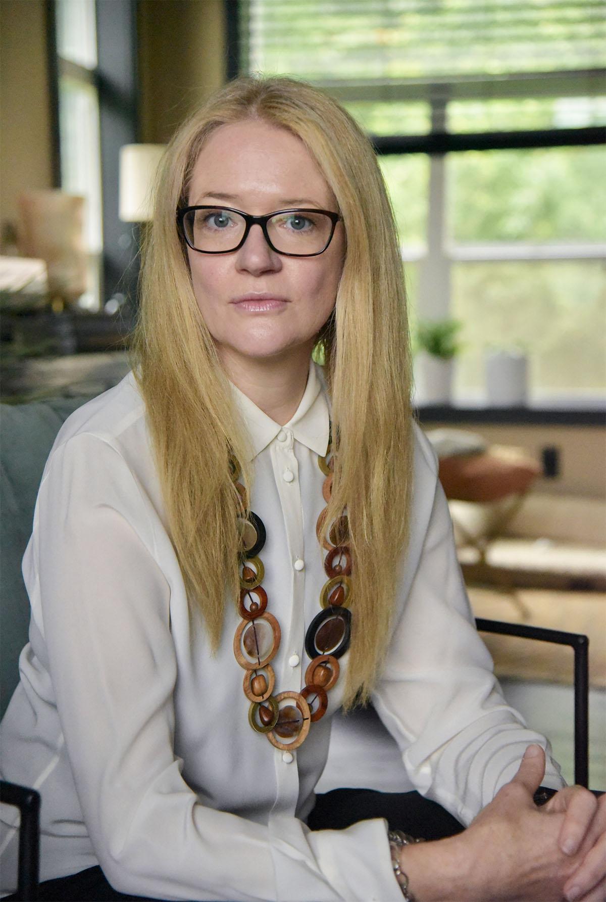 A woman with blond hair and glasses in a white blouse