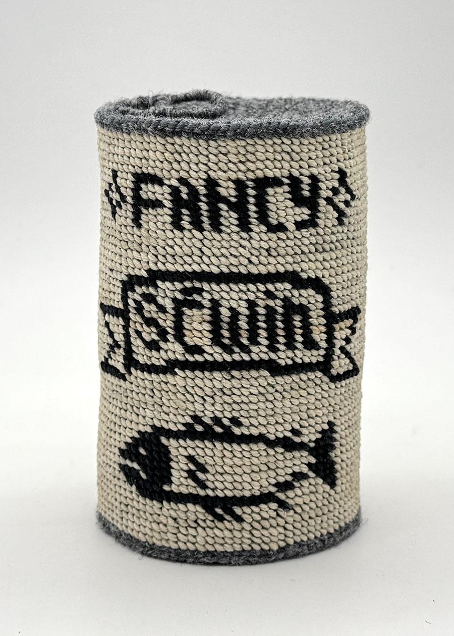 A cloth basket in the shape of a tin can covered in a textile with a pattern ready Fancy Sćwin and an image of a fish
