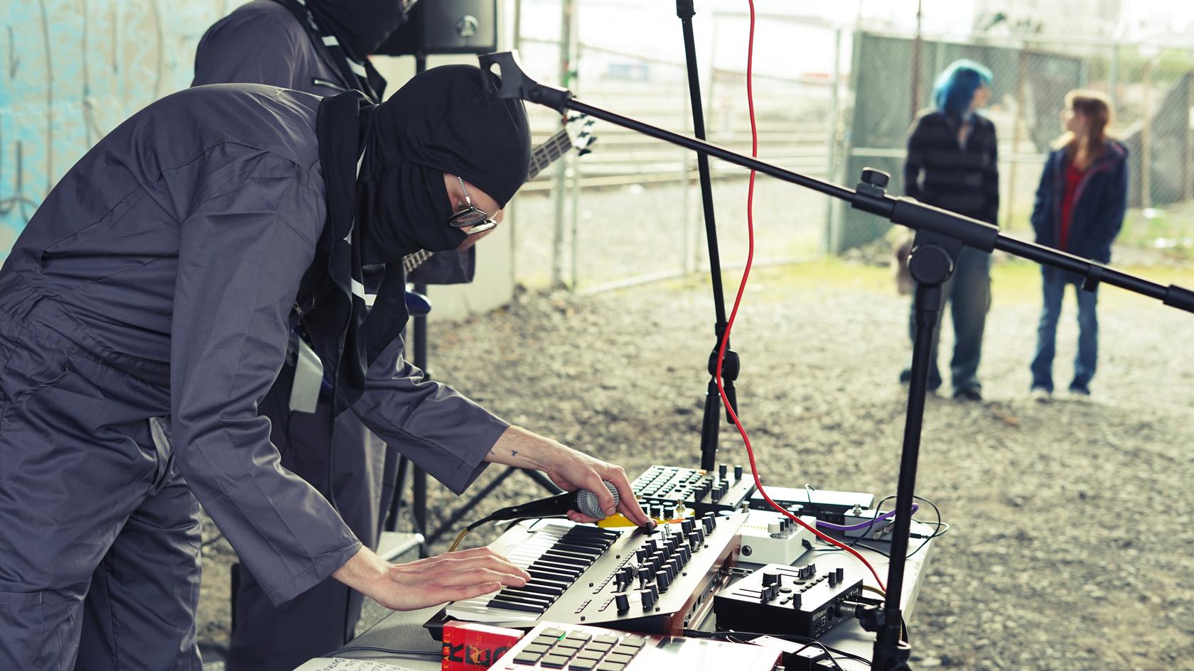 Photo of Stephen Kelley wearing a balaclava adjusting a sound board