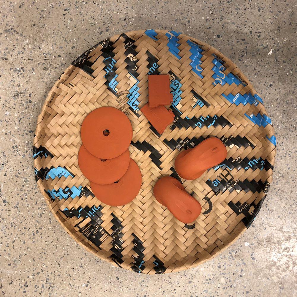 Woven basket with 3-d printed terra cotta objects inside