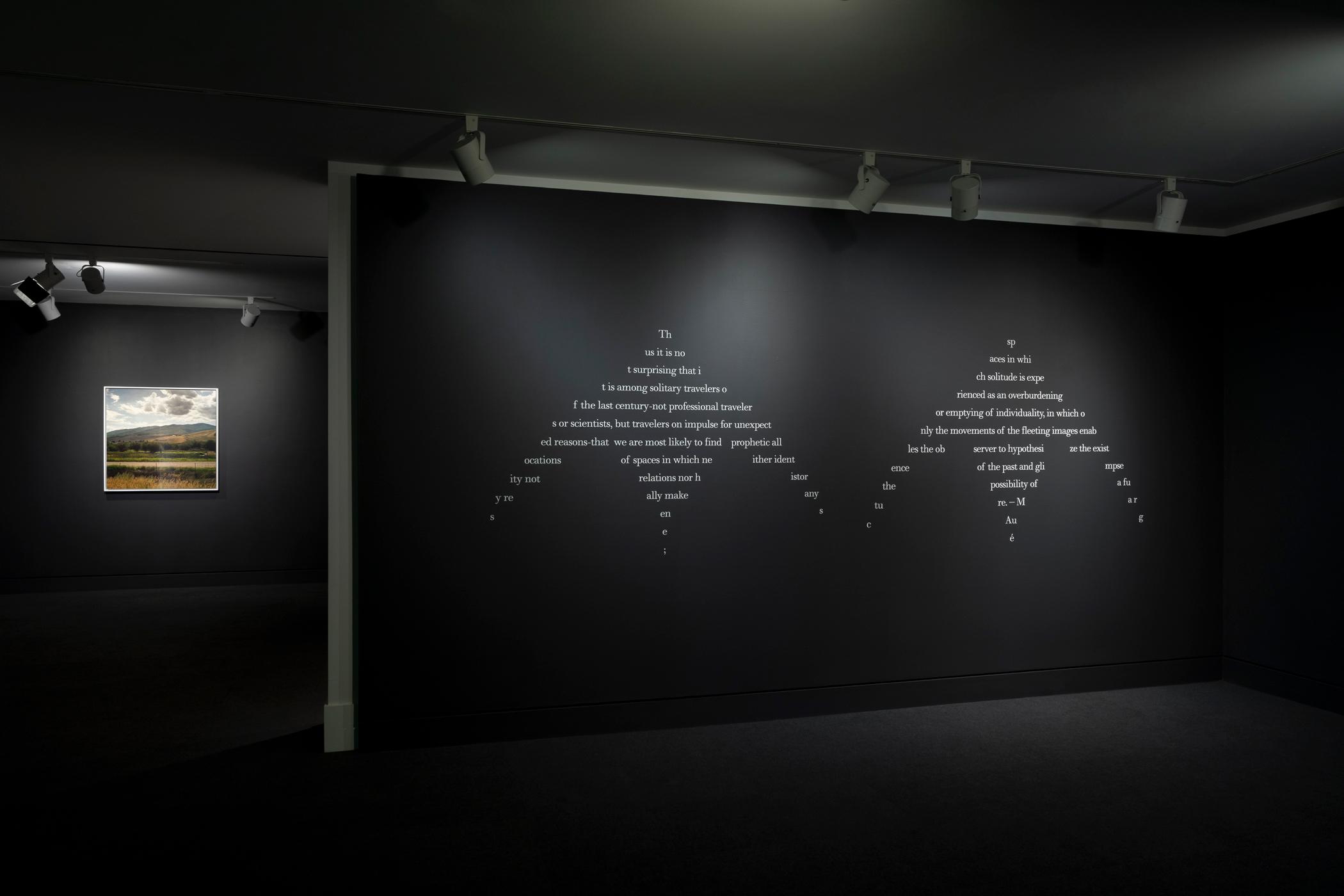 Installation photo of a visual poem on a gallery wall in Sky Hopinka: Subterranean Ceremonies