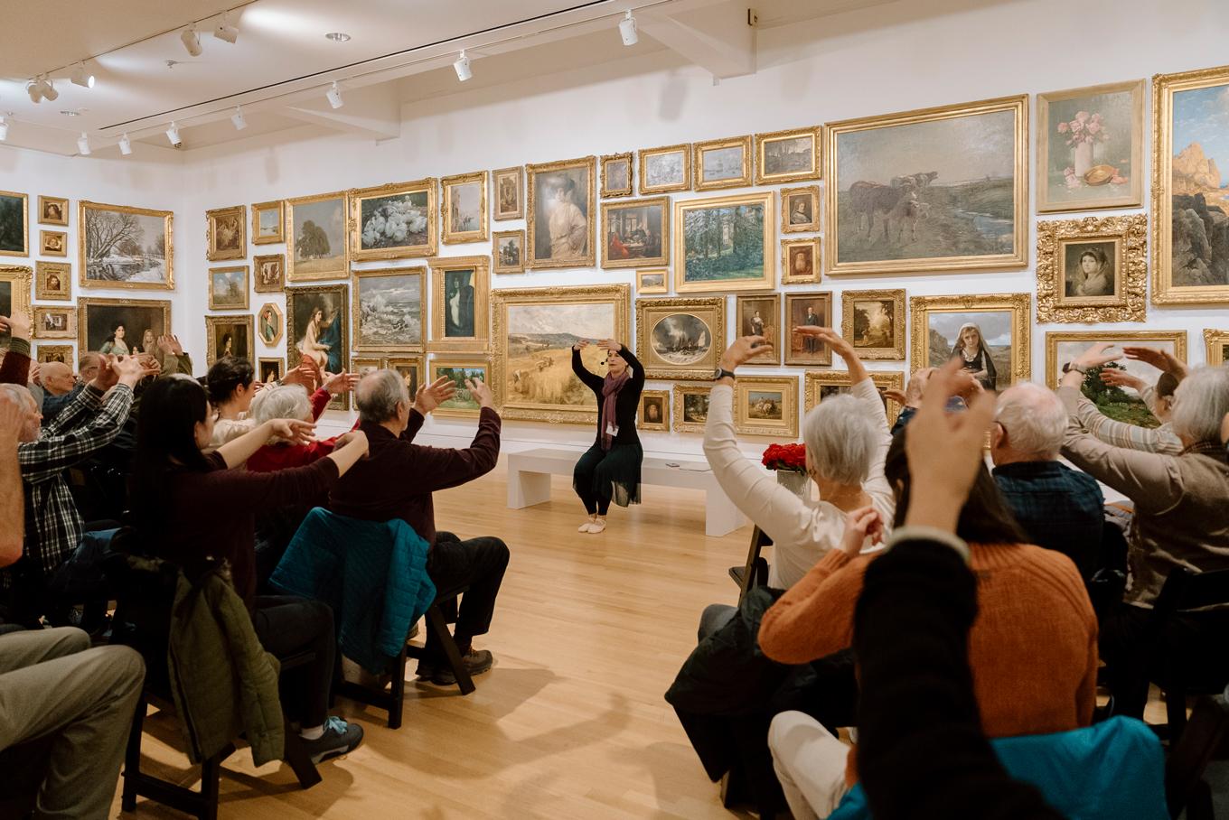 Dr. Julia Becke does seated movement with a group of participants in the Frye Salon