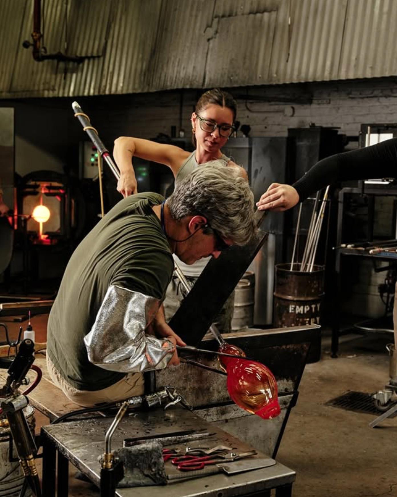 Sue Kim and Zeke Spier working together on a glass art piece in a hot shop
