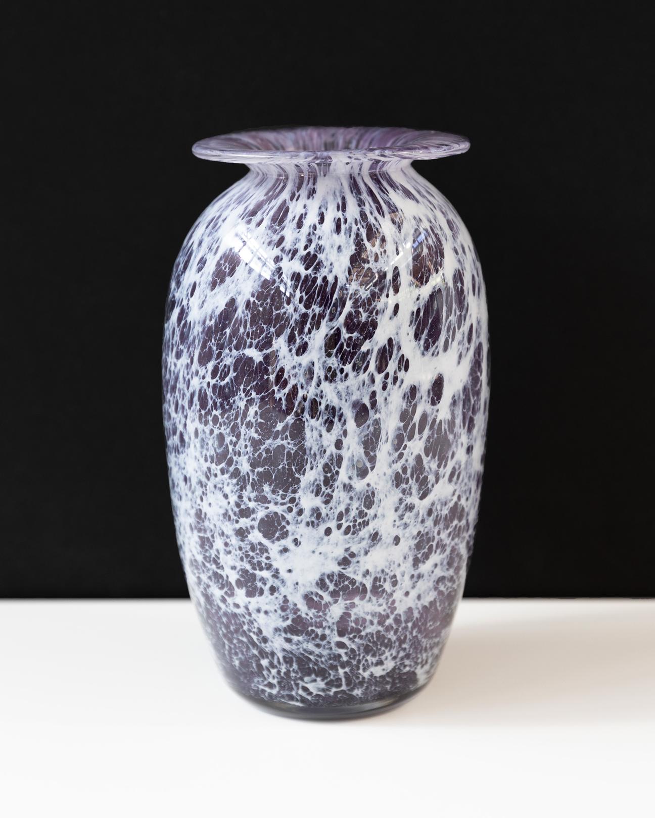 A black and white glass vase with a wide flat opening on top and web-like shapes on it