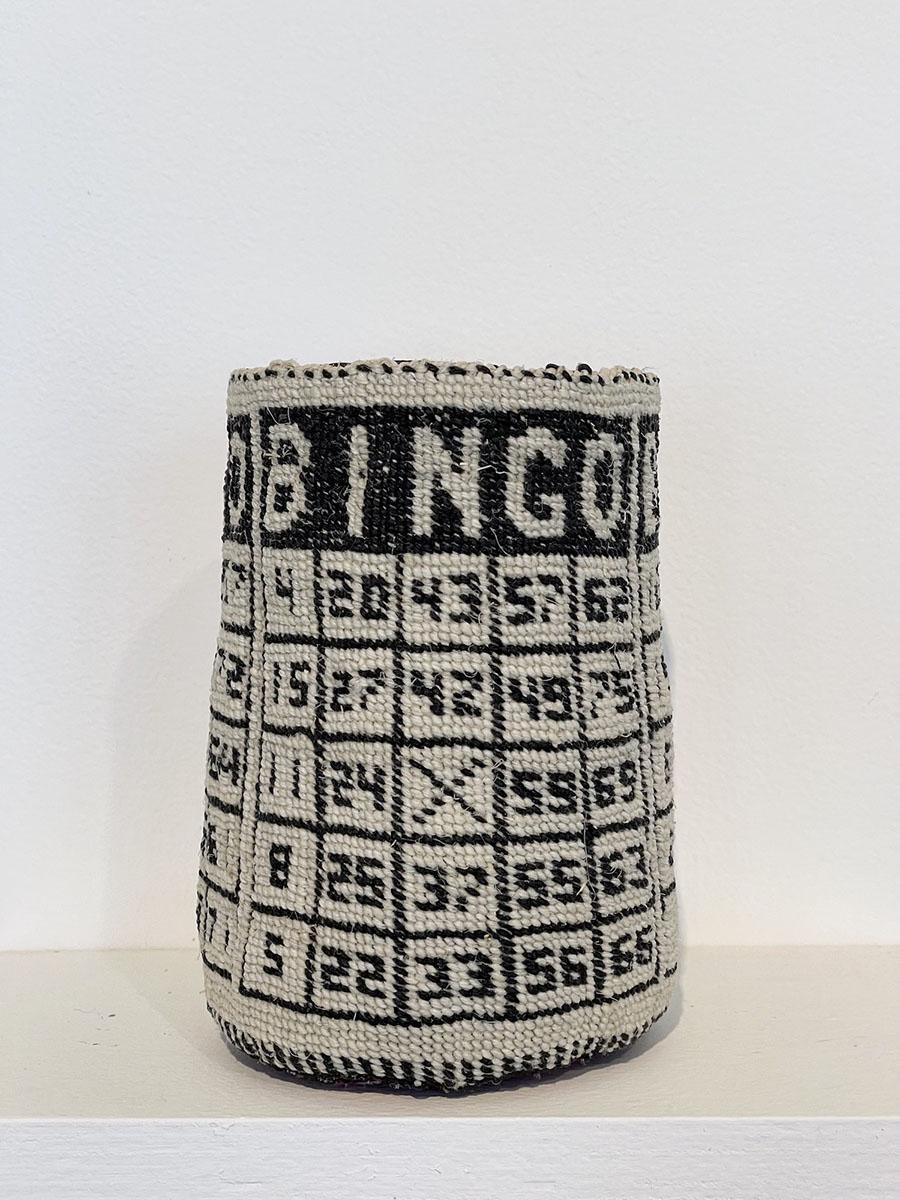 A cloth basket covered in a textile with a pattern of a bingo game board