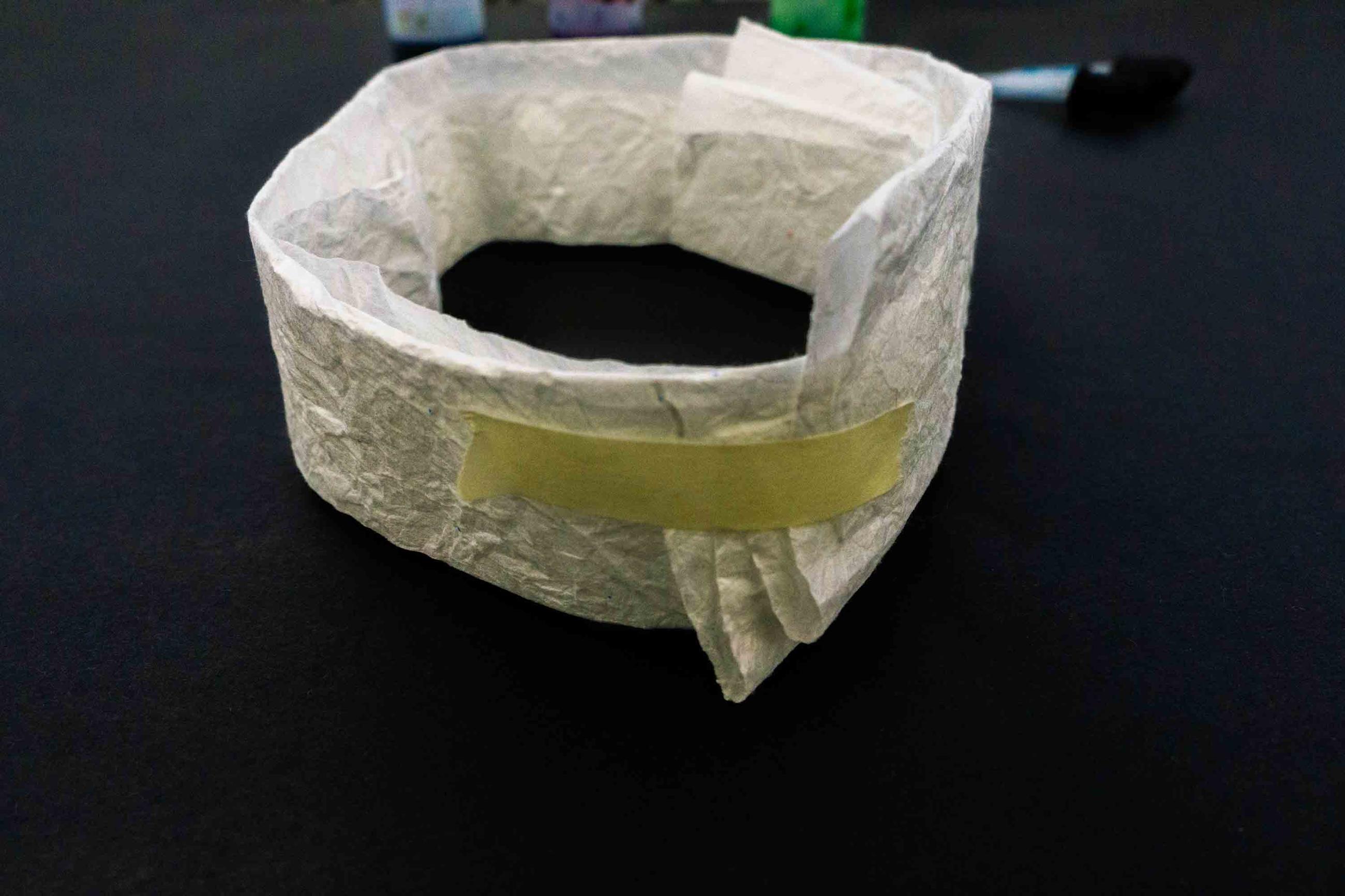 Photo of a folded piece of mulberry paper wrapped into a circle and secured with a piece of tape