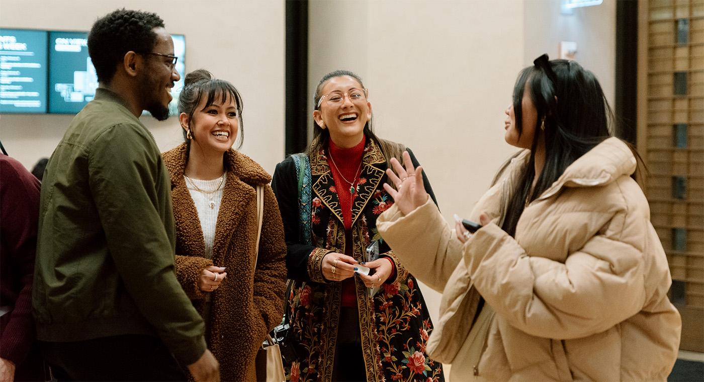 People wearing coats smiling and chatting in a large rotunda space