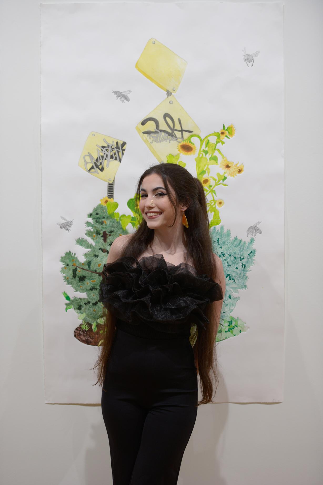Photo of Maddi Wareham smiling in front of a large colorful print of hers