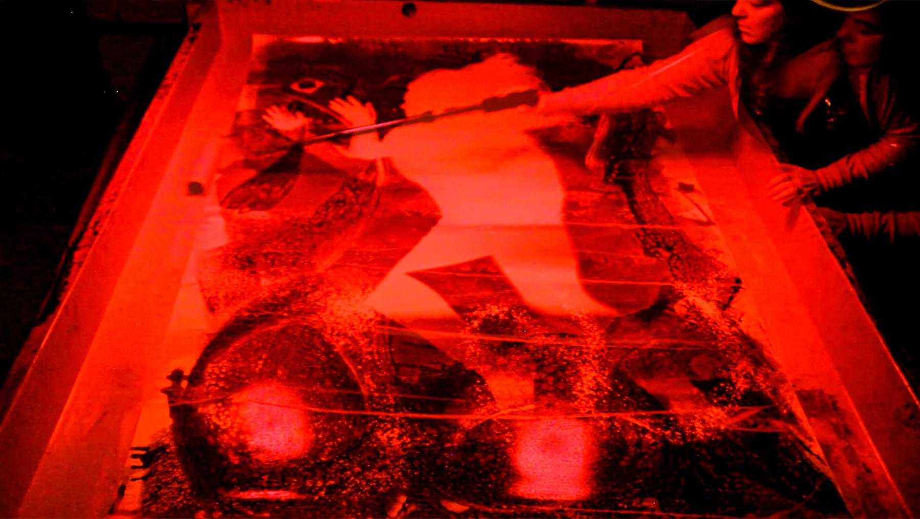 Rachel Wolf printing a self-portrait in her darkroom