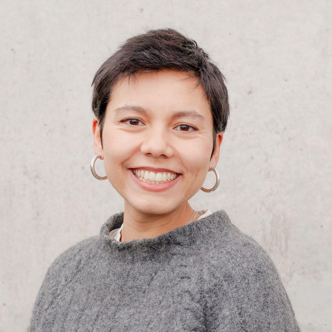 A headshot of a woman with short hair in a gray sweater