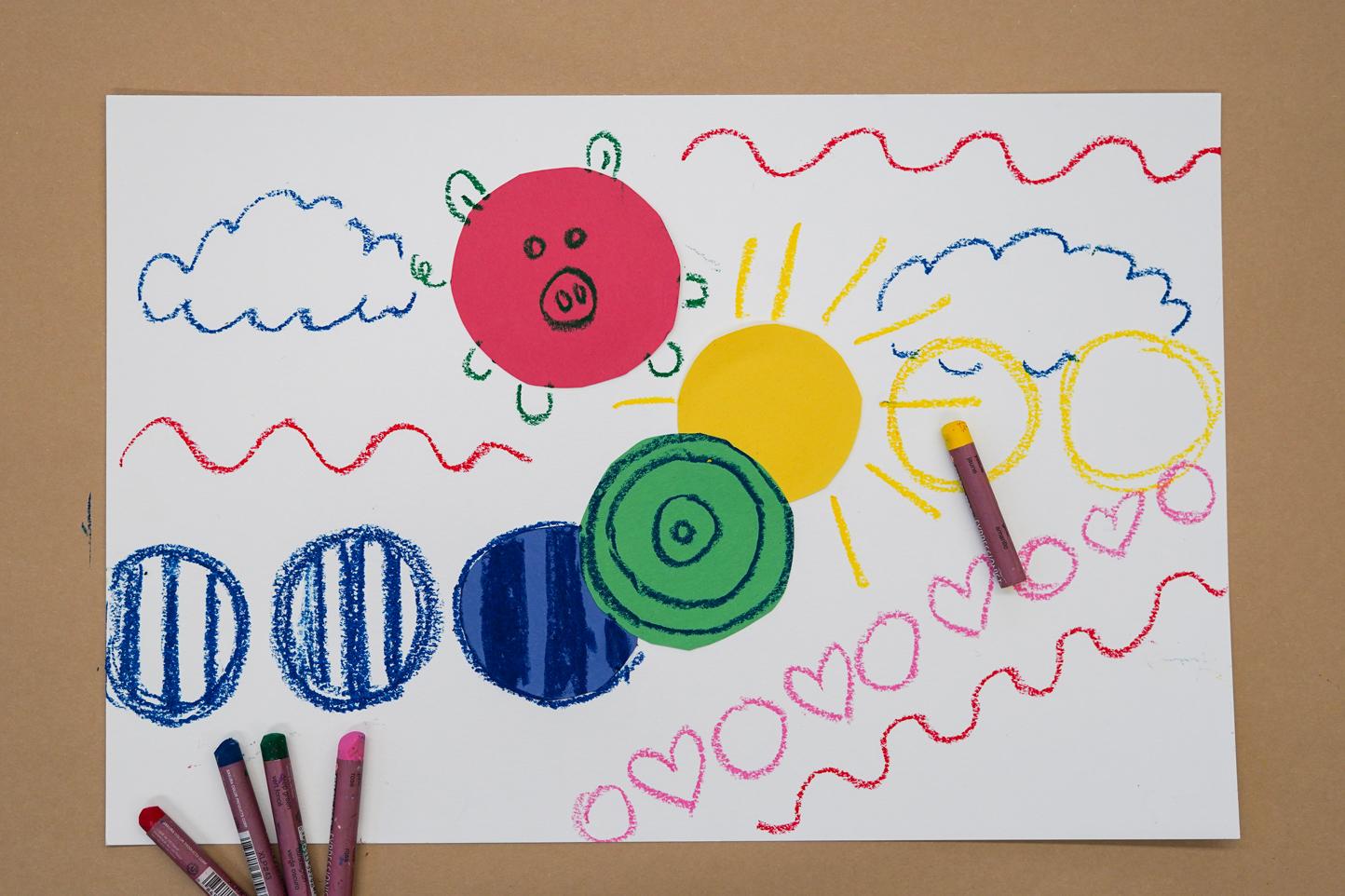 Photo of a piece of paper with circles of colorful construction paper on it and doodles in many colors