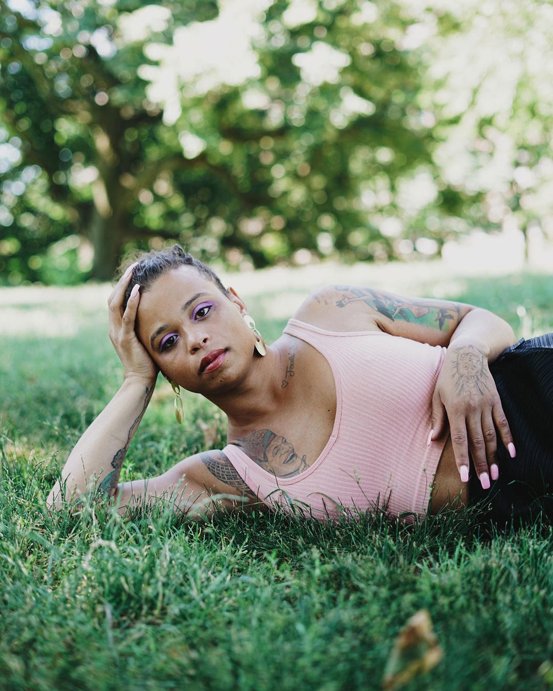 Photo of Tourmaline laying in the grass leaning on one arm