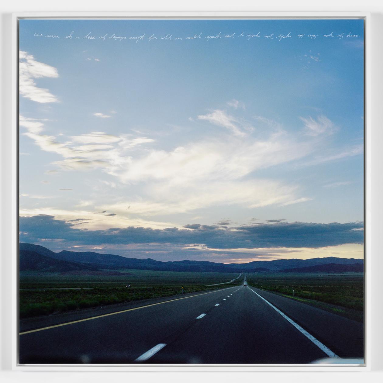 Photograph of an open highway with a large darkening sky above