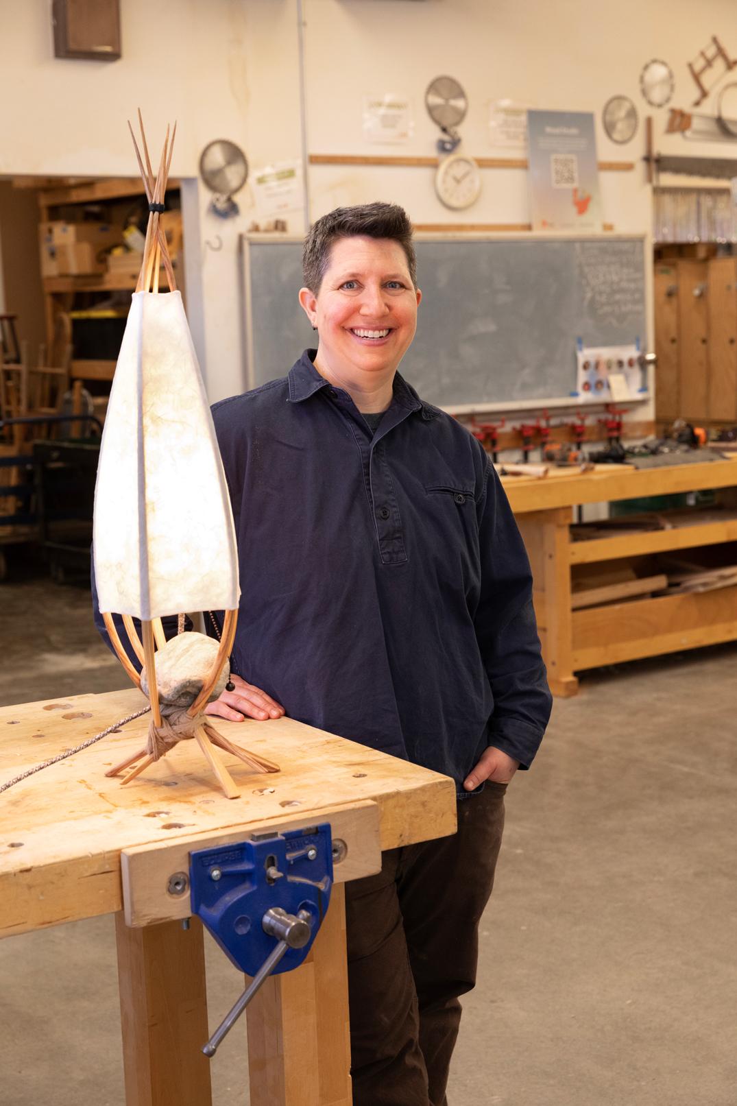 Kim McIntyre standing next to a sculptural lamp she made