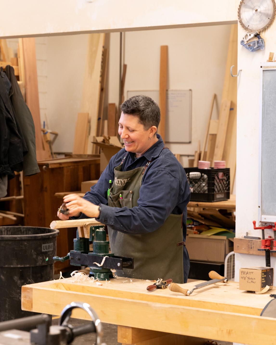 Kim McIntyre smiling and working in a woodshop
