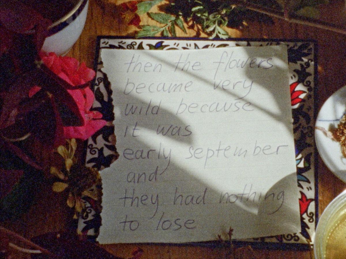 A still from a video of a piece of paper with a handwritten poem on a table