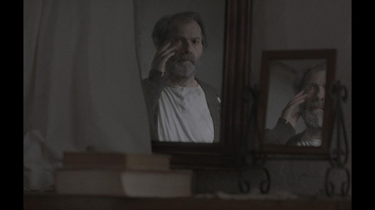 An older man looking in a pair of mirrors and touching his face