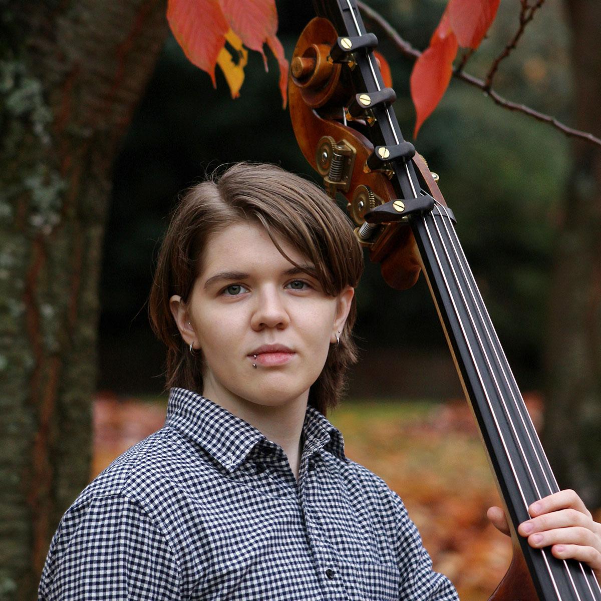 A person in a button up shirt holding a large upright bass
