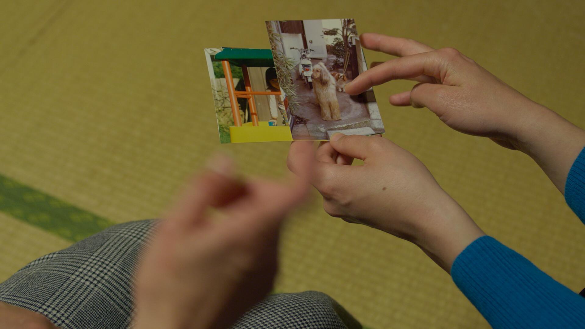 A view over two peoples' shoulders showing their hands holding small photo prints