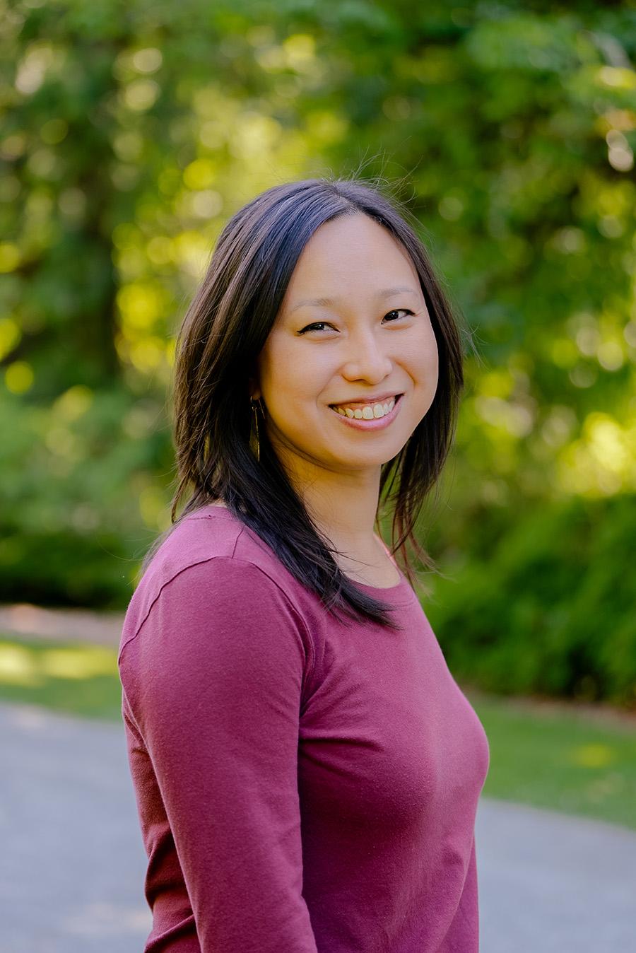 A smiling woman standing in front of trees
