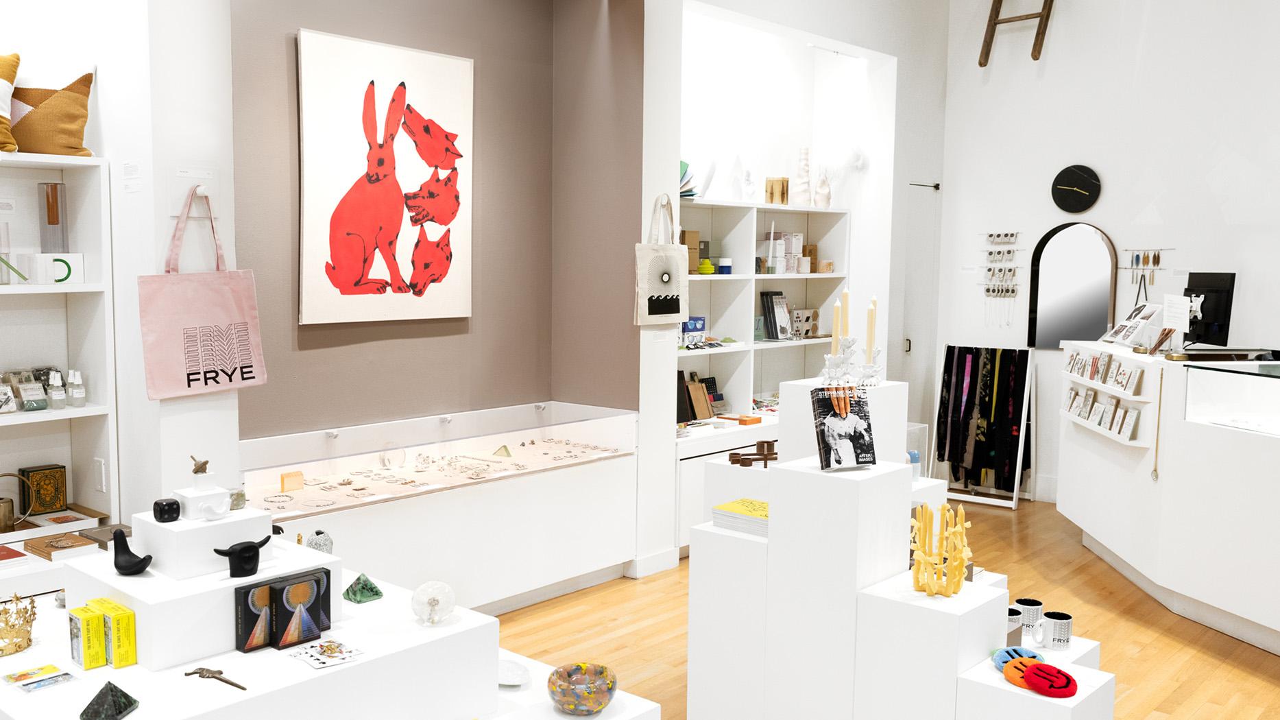 A small, well stocked shop with art related goods including a large artwork with red, stylized animals