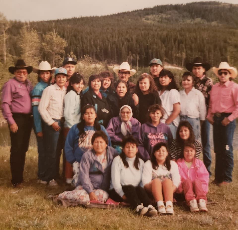 A large group family portrait on film. Many of the people are wearing western clothing including cowboy hats